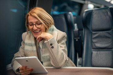 Smiling woman enjoying digital content on tablet during train travel