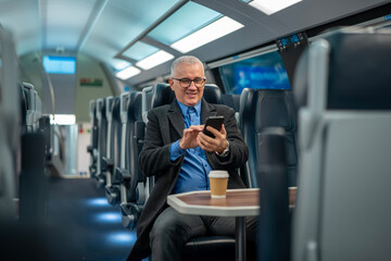 Mature businessman traveling by train using smartphone