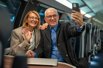 Senior couple making video call on modern train