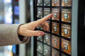 Hand choosing cappuccino coffee from automatic vending machine