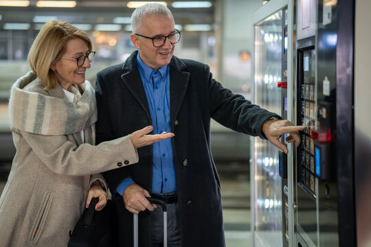 Senior couple buying from vending machine at station