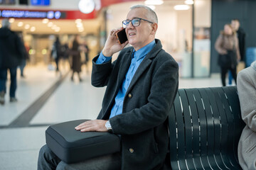 Mature man talking on smartphone at airport terminal