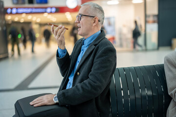 Mature man dictating voice note with smartphone