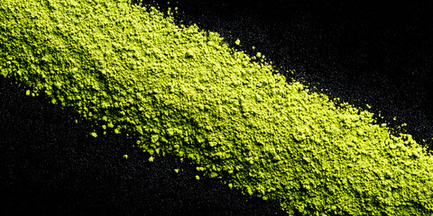 Abstract background with green matcha powder on a black background. Small and large particles. Natural probuct, banner.