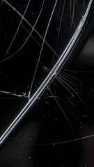Close-up of a severely cracked and scratched black glass surface, showing intricate damage patterns.