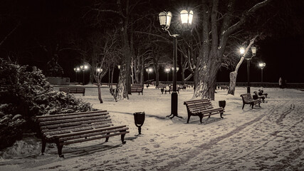 Winter Alley with Snow-Covered Benches and Street Lamps