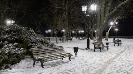 Winter Alley with Snow-Covered Benches and Street Lamps