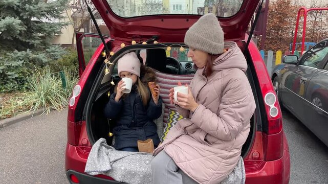 Enjoying a Cozy Car Picnic with Mother and Daughter during Winter Season