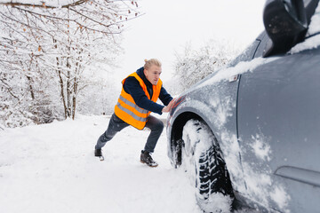  Male driver struggling to push his stalled vehicle in deep snow