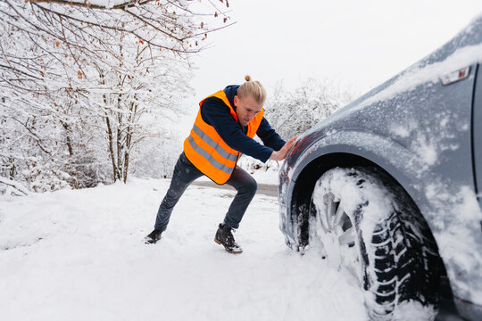  Male driver struggling to push his stalled vehicle in deep snow
