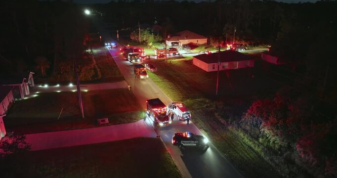 Fire engine trucks and ambulance vehicles responding to fire alarm at night. Investigation of carbon monoxide gas hazard at private house in USA.