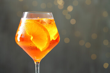 Glass of refreshing spritzer cocktail against grey background with bokeh effect, closeup. Space for text
