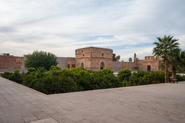Ancient mud brick city wall with palm trees in Marrakech, Morocco. Traditional North African architecture with warm earthy tones and clear blue sky, ideal for travel, history, and background use.