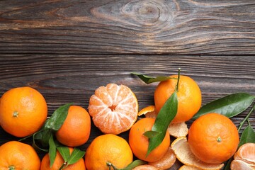 Fresh tangerines and green leaves on wooden table, flat lay. Space for text