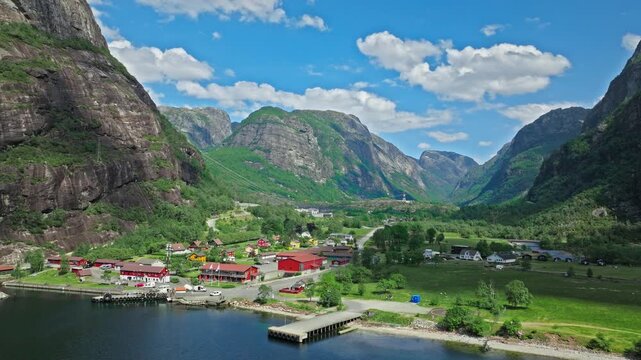 Drone view of Lysebotn village at the end of Lysefjord in Norway. Colorful houses, green fields and dramatic mountains create a peaceful fjord settlement in summer.