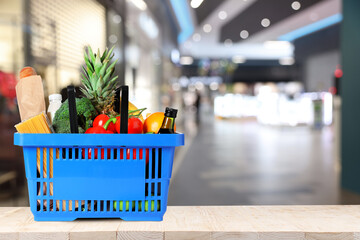Shopping basket full of products on table in supermarket. Space for text