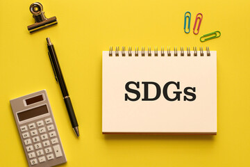 There is notebook with the word SDGs. It is an abbreviation for Sustainable Development Goals as eye-catching image.
