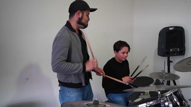 Teacher and student playing together on the same drum set, sharing rhythm and coordination. Music education, percussion learning, collaborative drums practice