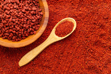 Organic red annatto seeds in spoon and bowl - Bixa Orellana