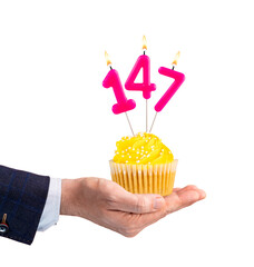 Hand handing a birthday cupcake - Pink candle, number 147 on a white background