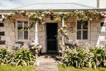 Stone cottage porch with flowering vines and grassy front yard