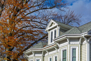 Beautiful gable dormer and ornate trim of a classic family home surrounded by autumn branches in Boston, Massachusetts, USA  © Baharlou