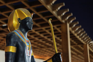 Black pharaoh statue with golden headdress and staff