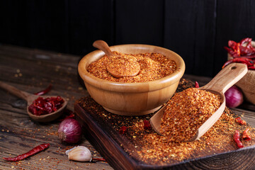 A close-up image of chili powder in a wooden spoon, spices for Asian cooking, arranged on a wooden table, conveying the concept of spicy food.