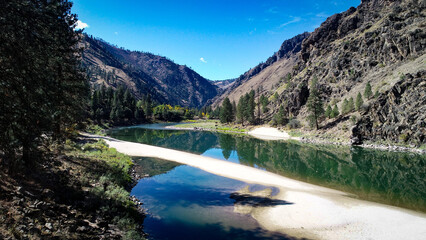 drone photo of Salmon River Canyon upstream from Riggins ID with white sandy beaches and beautiful clear reflection of the canyon walls and blue sky
