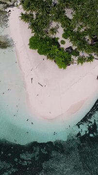 Sandy island with palm trees surrounded by turquoise shallow waters and anchored boats nearby. Guyam Island. Siargao, Philippines.