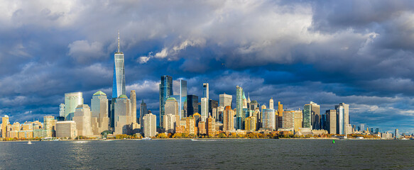 Panoramic Lower Manhattan skyline over Hudson River under dramatic clouds in NYC