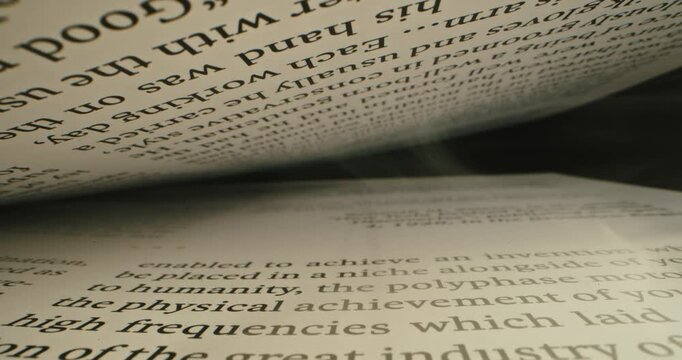 Extreme close-up view of a text in English between the pages in a book, shot inside a book with laowa probe lens with dolly shot. Sliding over lines with text. Reading book. Macro shot