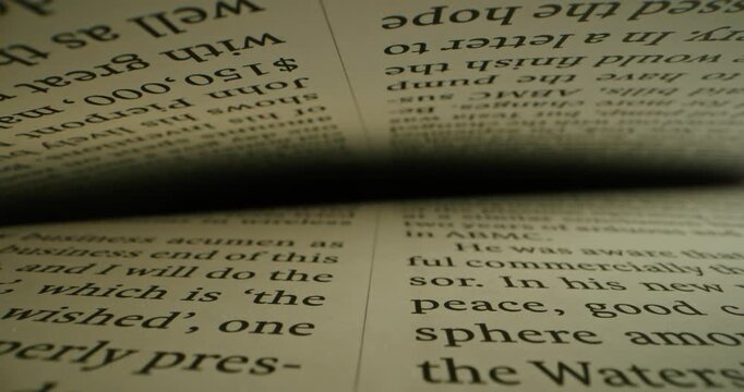 Extreme close-up view of a text in English between the pages in a book, shot inside a book with laowa probe lens with dolly shot. Sliding over lines with text. Reading book. Macro shot