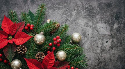 Poinsettia arrangement placed on a dark textured concrete surface with fir branches, pine cones, red berries and silver baubles, leaving empty space on the right suitable for text and design layouts