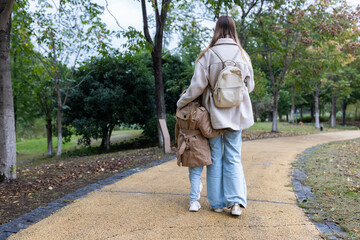Obraz premium Woman and young girl walking together on a park path in autumn