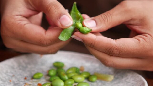 Closeup of Hands shelling edamame