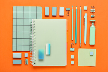 Different rubber erasers with notebooks and stationery on orange background