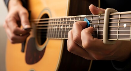 Fototapeta premium Close up of a person playing an acoustic guitar with a capo on the neck.
