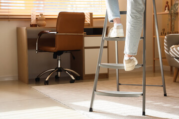 Legs of woman climbing stepladder in room, back view © Pixel-Shot