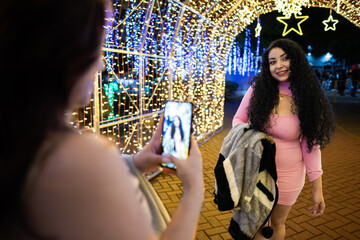 Woman posing for smartphone photo with christmas lights
