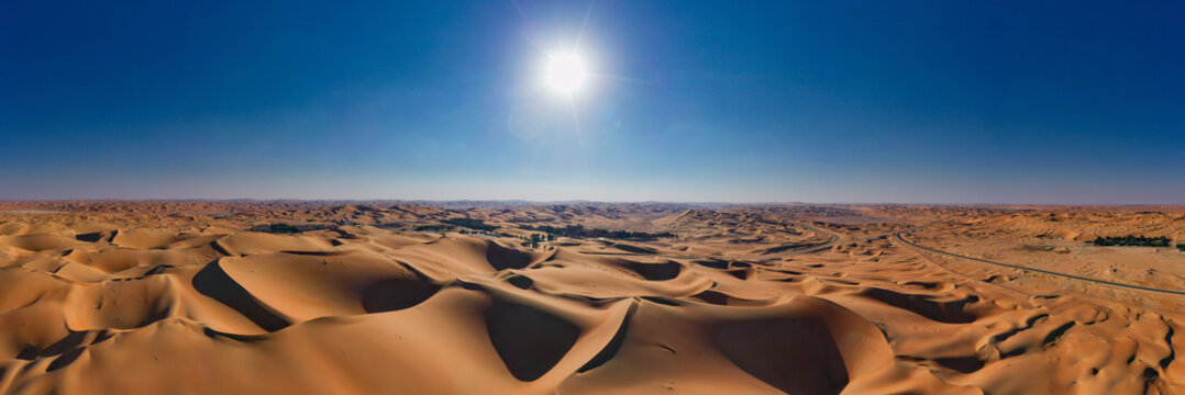 Expansive aerial panorama of rolling orange sand dunes in the Liwa Desert, Empty Quarter, UAE. Beautiful natural patterns and desert landscape under a clear sky