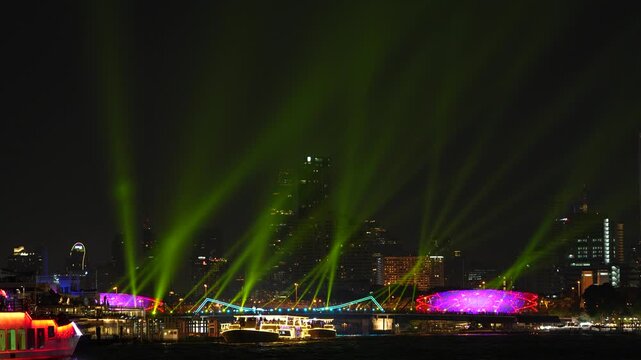 Night river festival with colorful laser beam over city skyline and light show cruise along waterfront, illuminated bridge and boat, neon glow nightscape reflection celebration Bangkok Thailand.