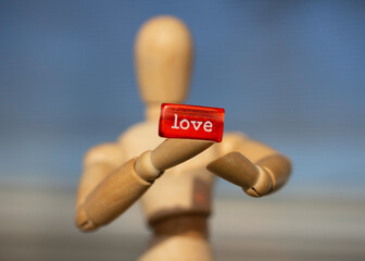 Wooden mannequin holding a red sign saying love
