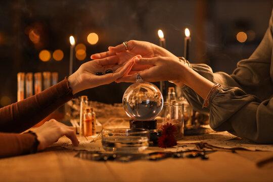 Fortune teller reading woman's palm at table