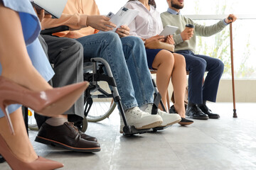 Job applicants with man in wheelchair waiting for interview at office