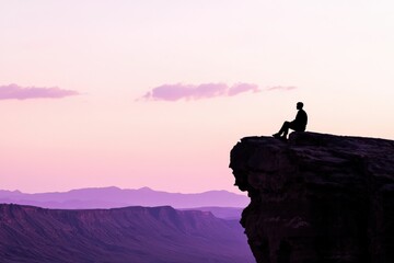 断崖に座る人物のシルエット