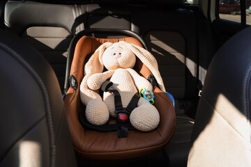 Fastened toy bunny in car seat for baby