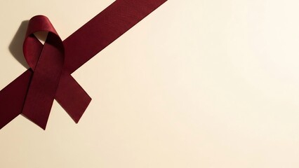 Symbol of hope: a deep red ribbon tied in a bow on a soft cream background, evoking awareness and support