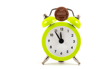 A US one cent coin and an alarm clock on a white background