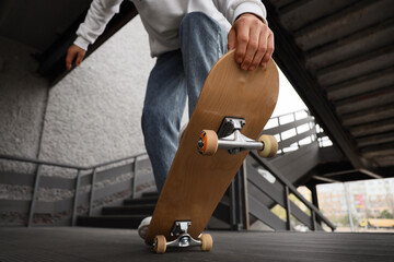 Young man with skateboard outdoors, closeup © Pixel-Shot